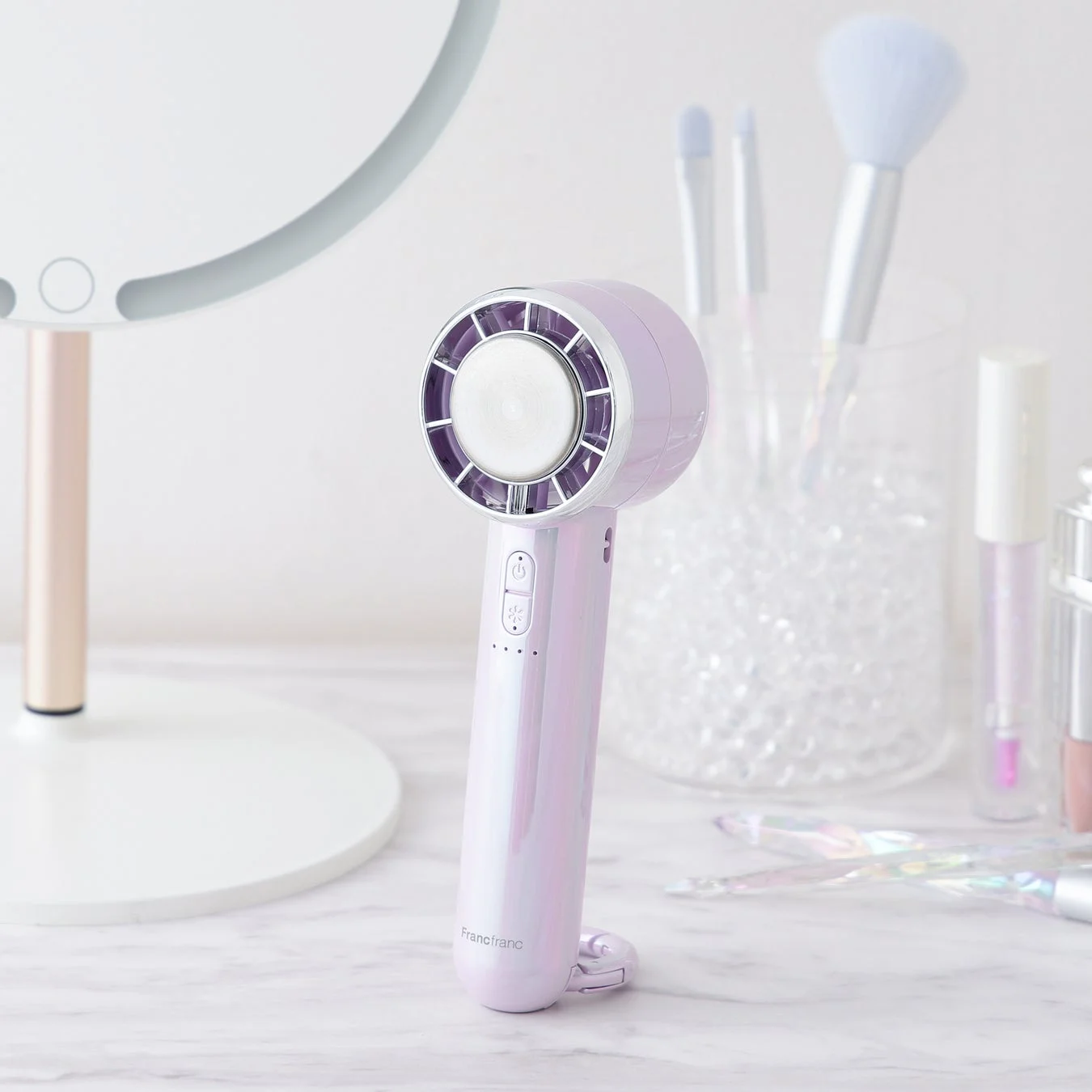 パープルとオーロラカラーが特徴的なフランフランのハンディファンがドレッサーに置かれています