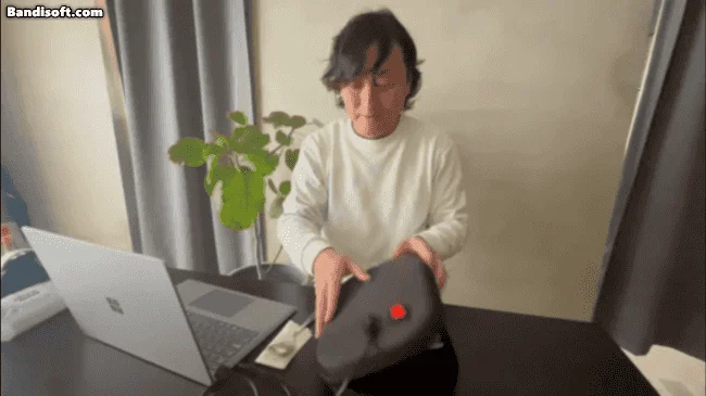 デスクで黒いデバイスを操作する男性