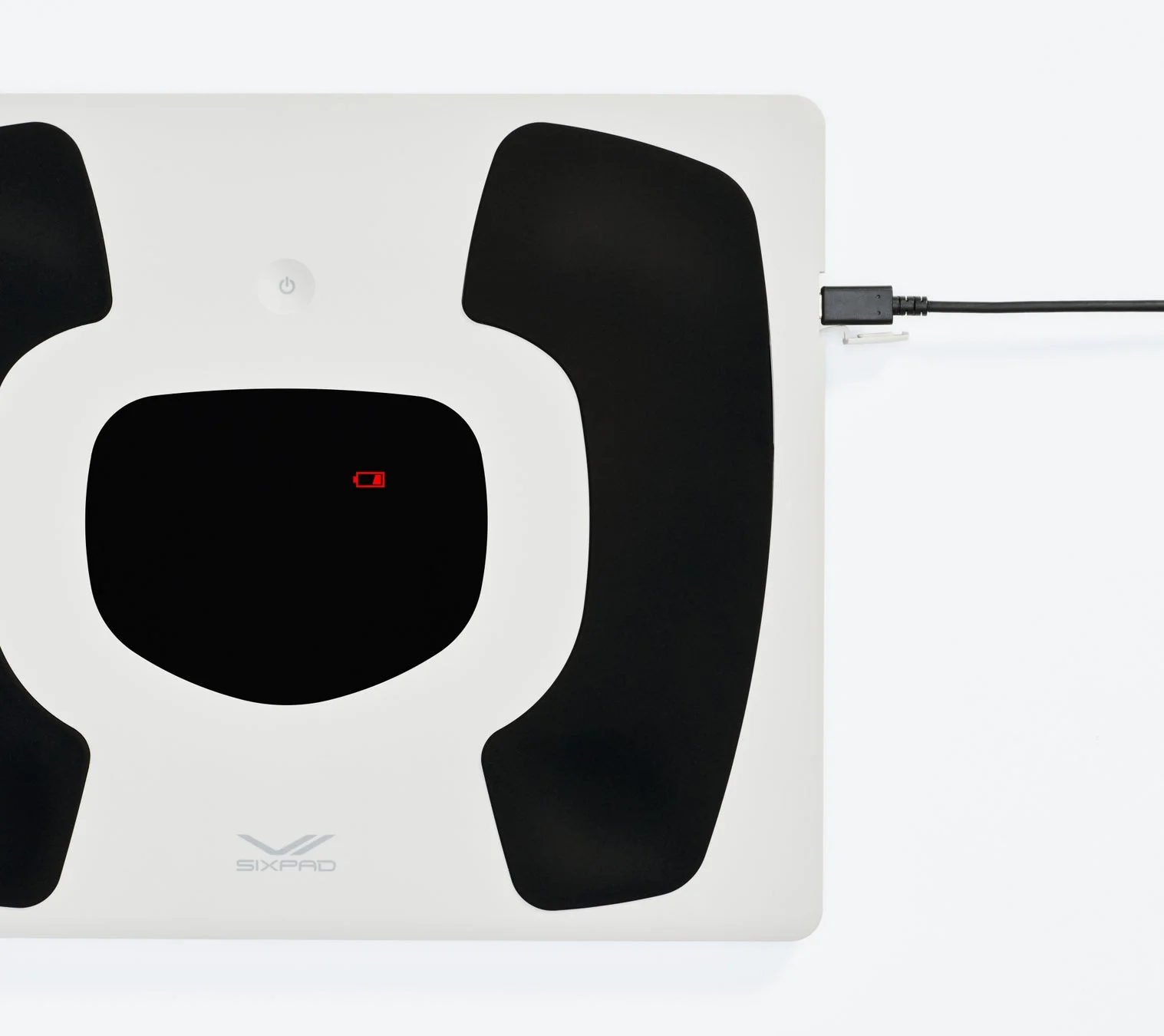 白と黒のデザインが特徴的な体組成計が充電されており、バッテリー残量が少ないことを示す赤いアイコンが表示されています。SIX PADのロゴも確認できます。
