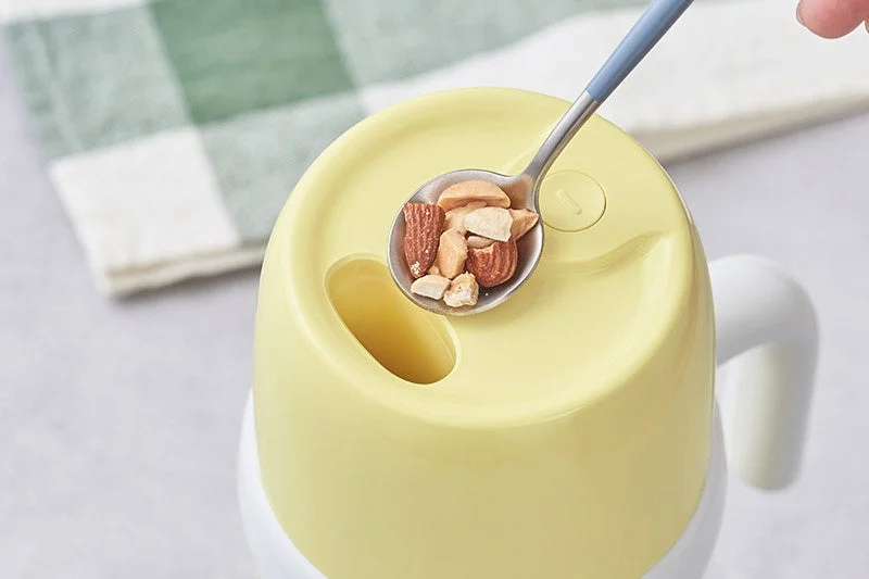 ナッツをスプーンでマグカップに入れる様子