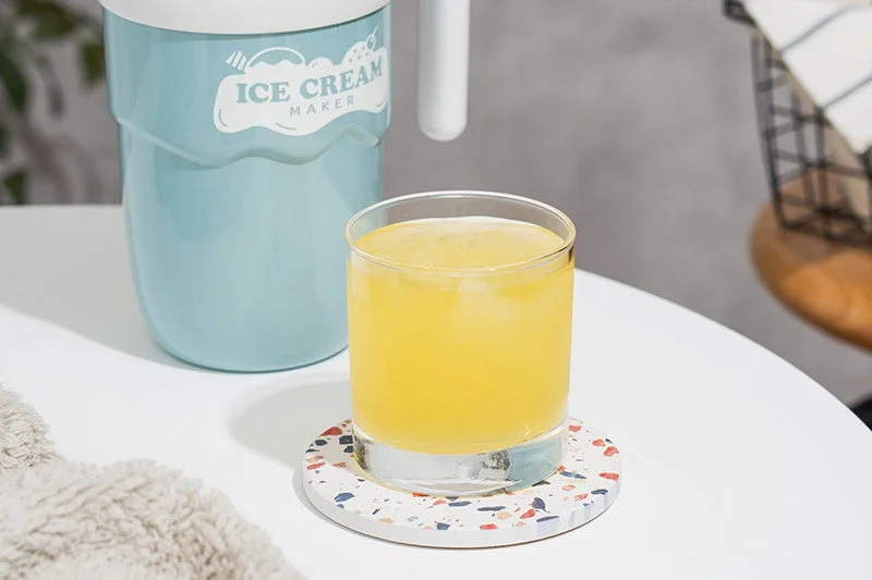 水色のアイスクリームメーカーと黄色い飲み物が入ったグラス