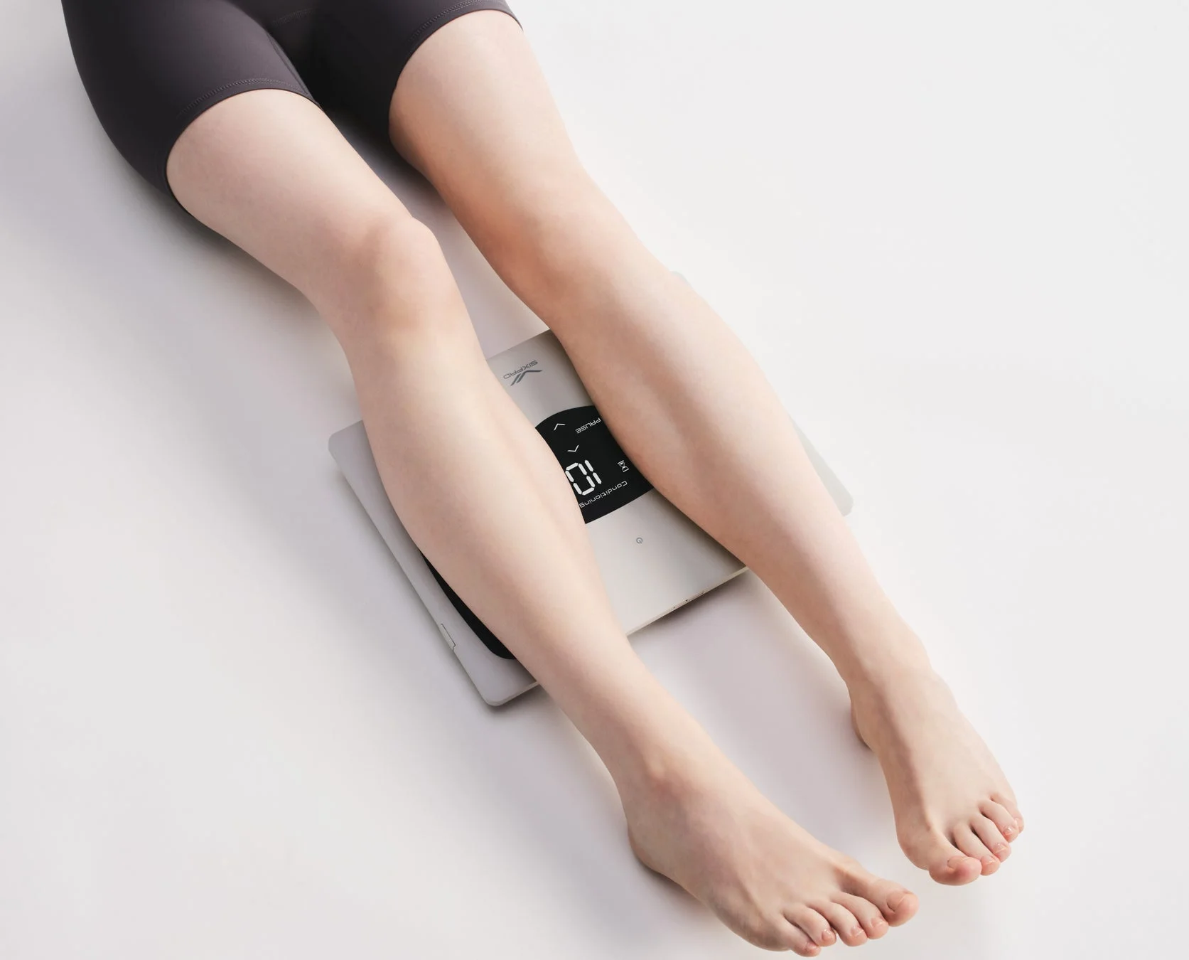 白い背景の上で、スマートスケールに乗せられた女性の脚が写っています。スケールには「SIXPAO」のロゴと「Conditioning 10」の表示が見え、健康管理やフィットネス活動を示唆する画像です。