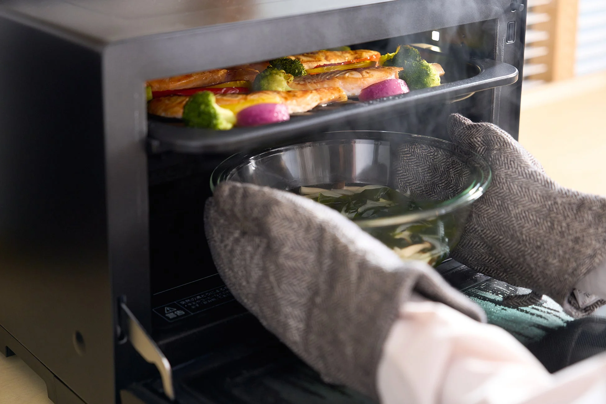 スチームオーブンで鮭と野菜を調理している場面