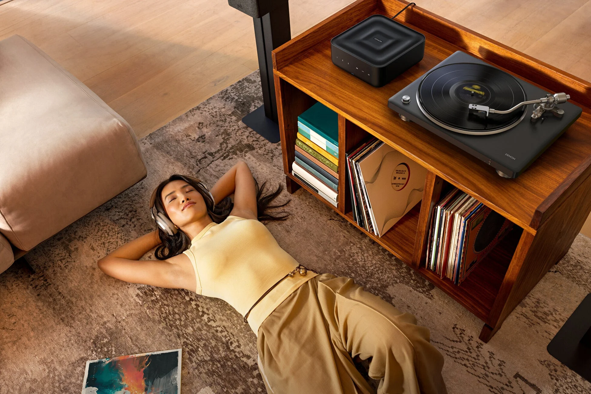 モダンなリビングでヘッドホンをしてリラックスして音楽を聴く女性。近くにはデノンのレコードプレーヤーと多数のレコード。