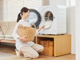 女性が乾燥機に洗濯物を入れている様子