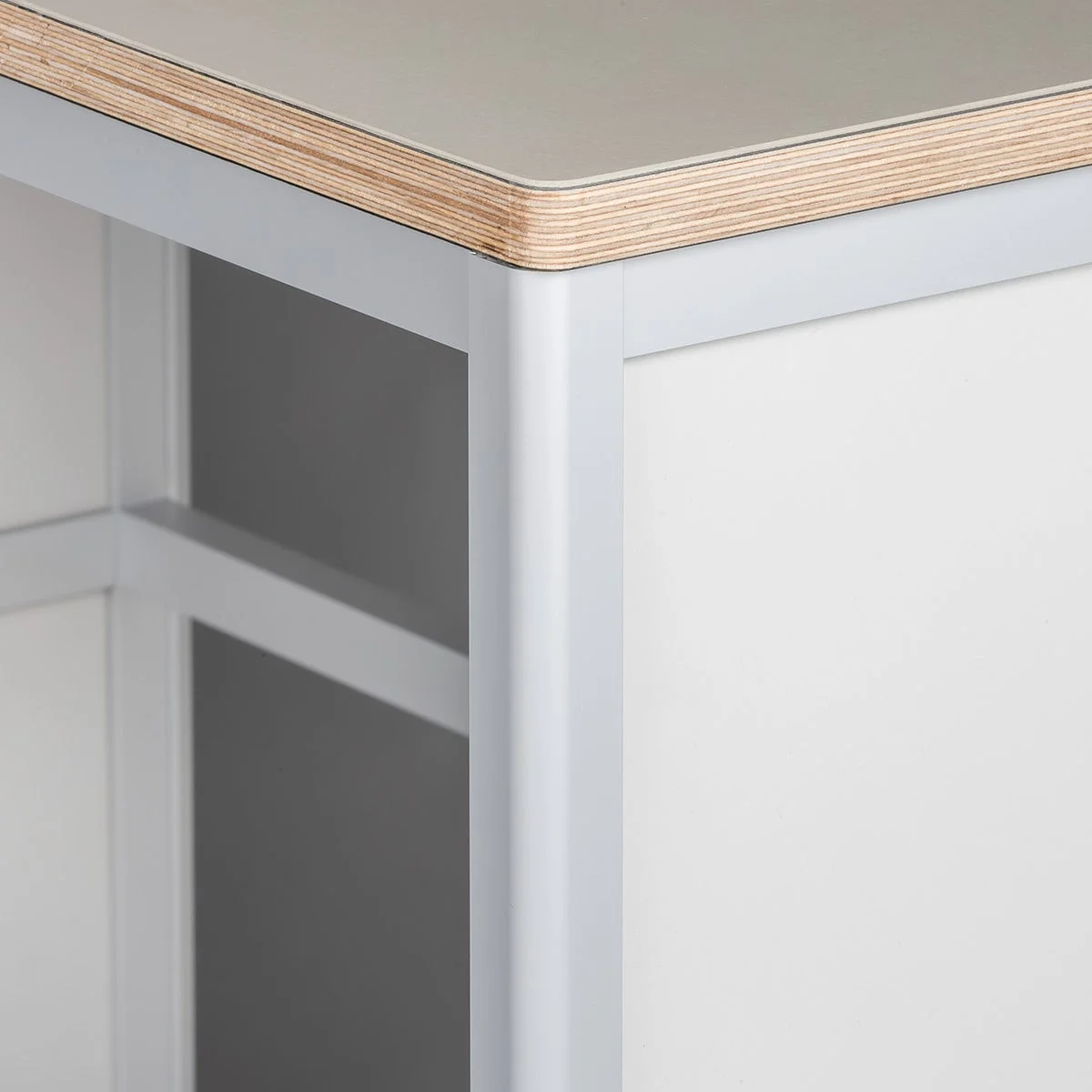 木材の積層が見える天板と、ライトグレーのスチールフレーム、白いパネルで構成された家具のクローズアップです。シンプルでモダンなデザインが特徴です。