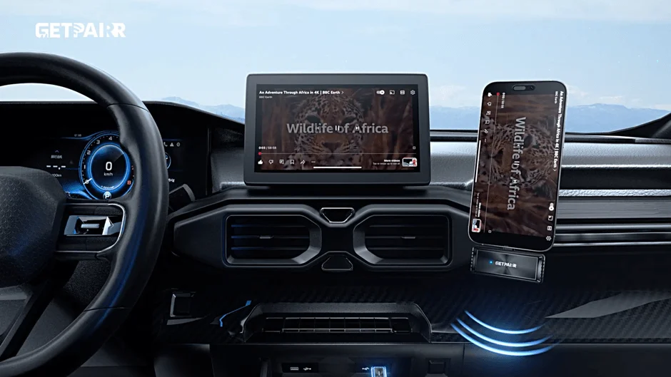 現代的な車のダッシュボード。中央のタブレットと右のスマートフォンで、BBC Earthの自然番組「Wildlife of Africa」が再生されている。デジタルメーターは0 km/h表示。車内でのエンターテイメント利用シーン。