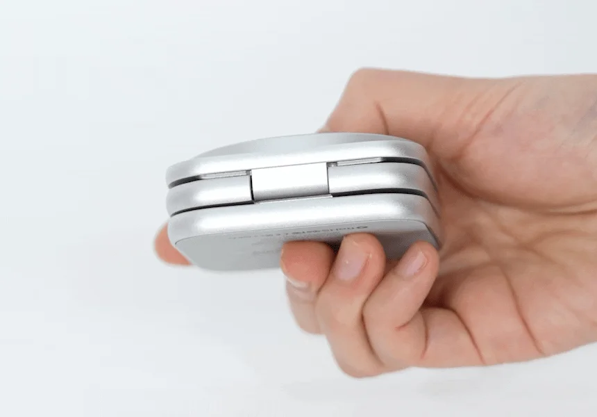 手が銀色の折りたたみ式デバイスを握っている様子を捉えた画像です。