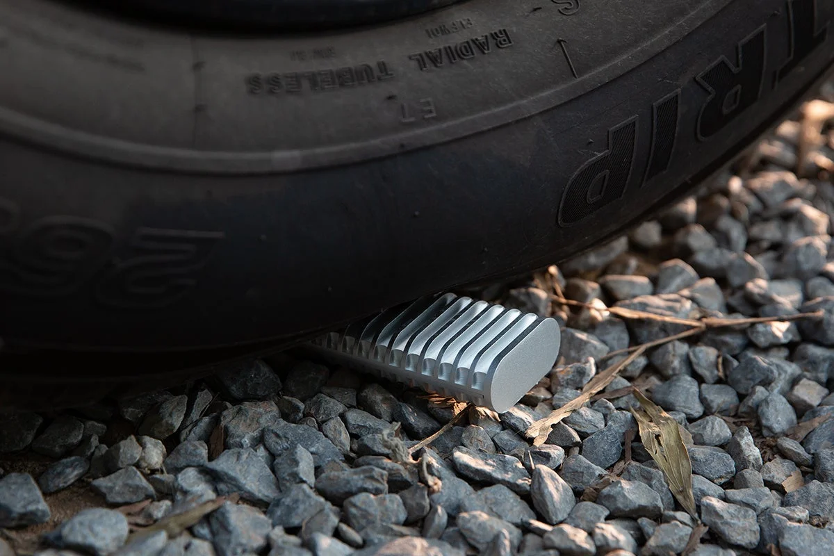 車のタイヤと、その下に置かれた銀色のリブ付き物体