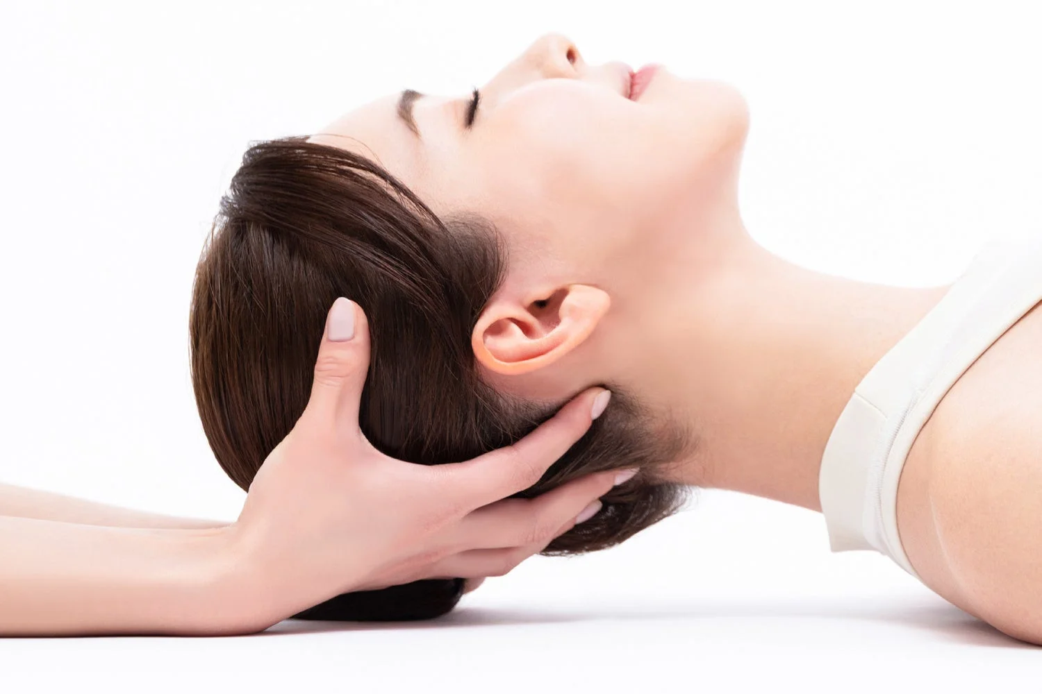 女性が目を閉じて頭や首のマッサージを受けている