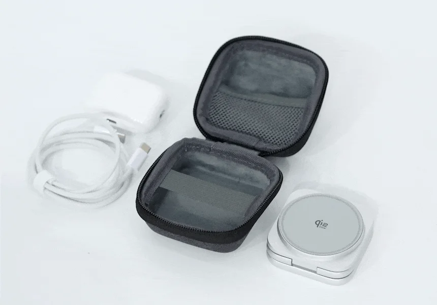 白い背景に、ワイヤレス充電器、USB-Cケーブル、ACアダプター、そしてそれらを収納するための黒いポーチが広げられています。