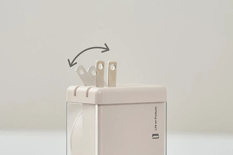 折りたたみ式のプラグを備えた電源アダプターのクローズアップ画像です。プラグの可動性を示す矢印が描かれており、コンパクトに収納できる機能性を表現しています。