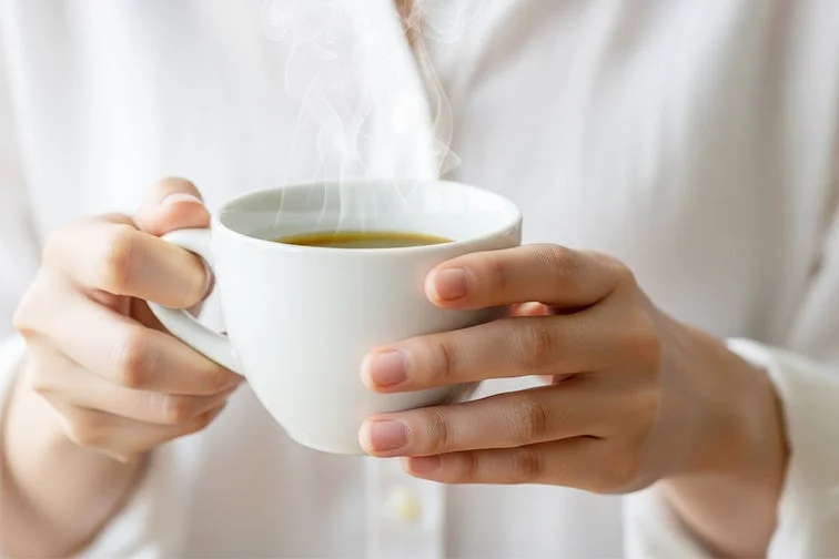温かい飲み物が入ったカップを持つ手