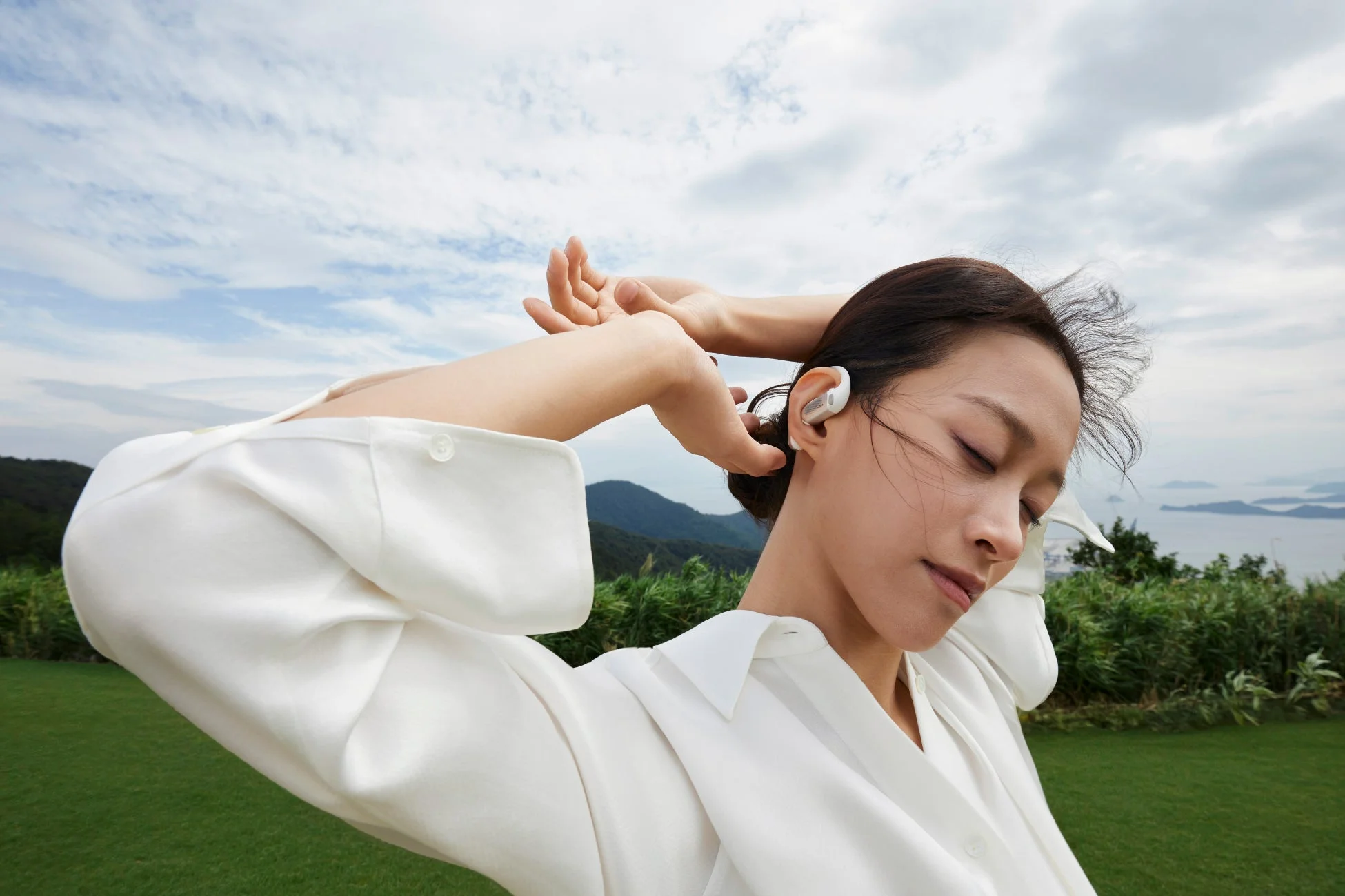 屋外でShokz OpenFit Proを装着しリラックスする女性