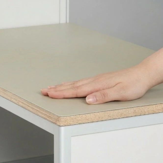 一枚の画像には、ベージュ色の平らな表面に置かれた人の手が写っています。素材の質感や触り心地を表現しているように見えます。