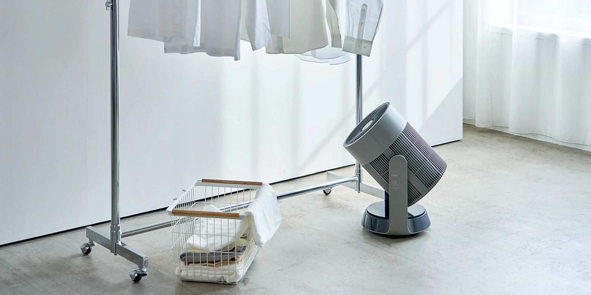 白いシャツが吊るされた物干しラックと衣類乾燥用のサーキュレーター