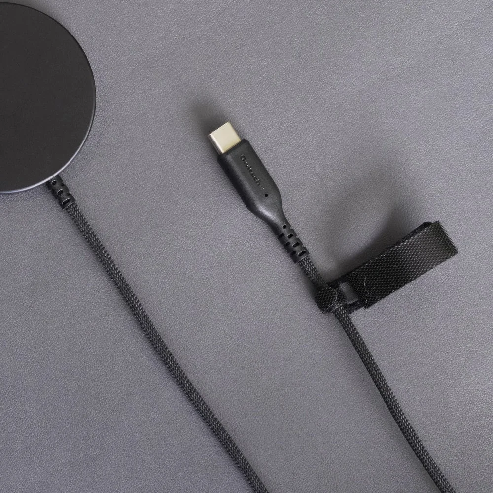 グレーの背景に置かれた黒いワイヤレス充電器と、それに接続された編組USB-Cケーブルのクローズアップ画像です。ケーブルにはケーブルタイが巻かれています。