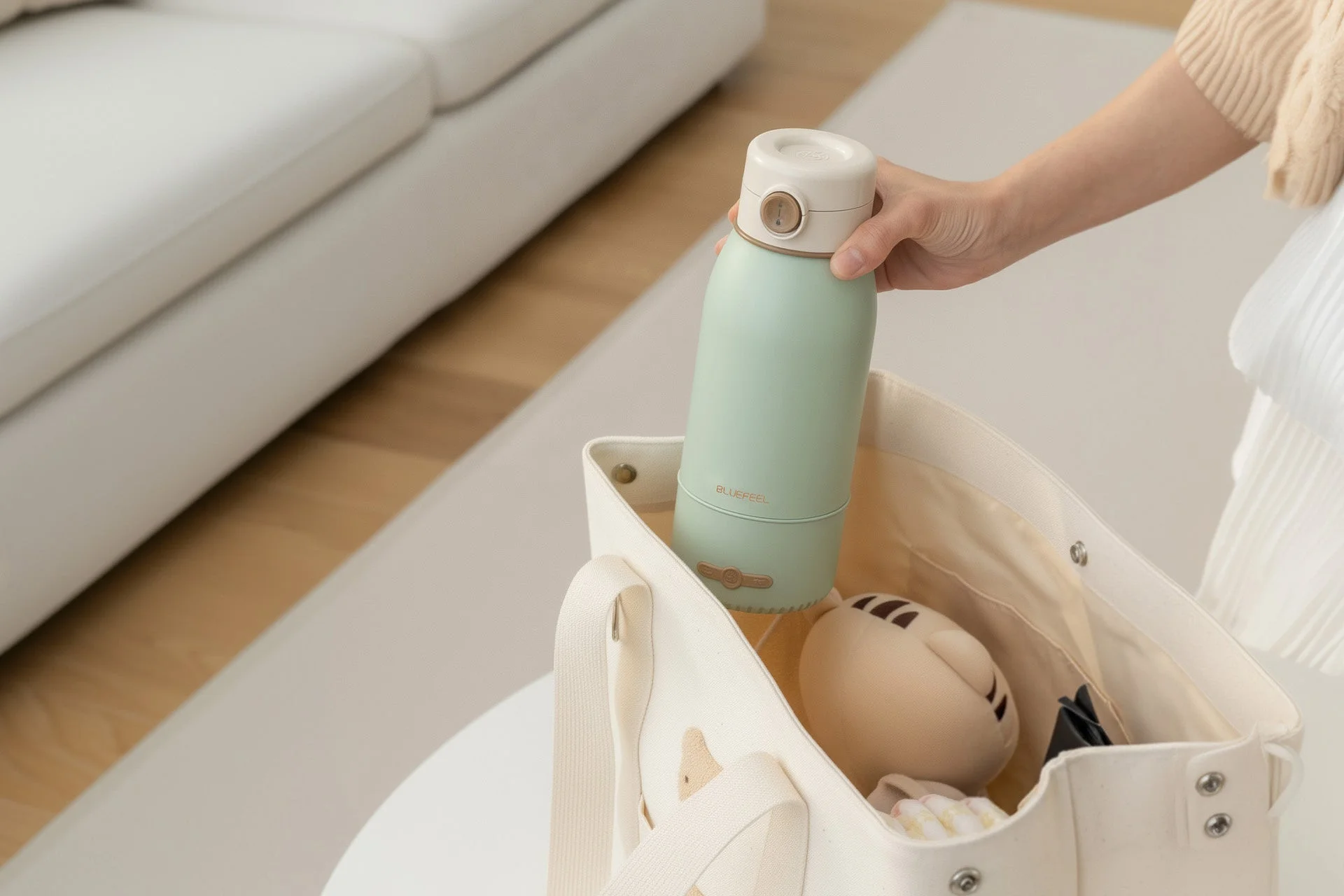 ミントグリーンのボトルをトートバッグに入れる女性