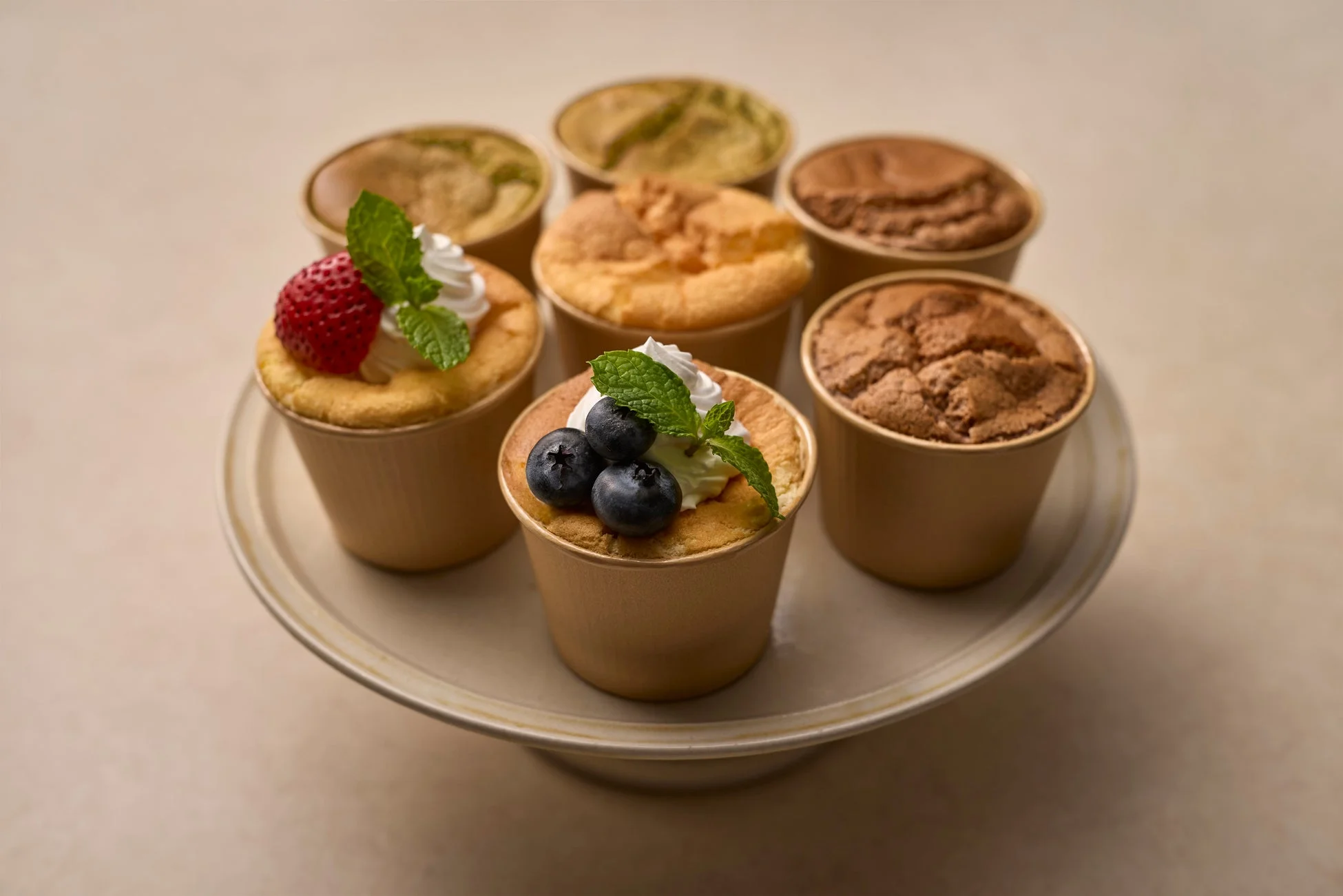 カップに入った様々なフレーバーのシフォンケーキやカップケーキがケーキスタンドに並べられています