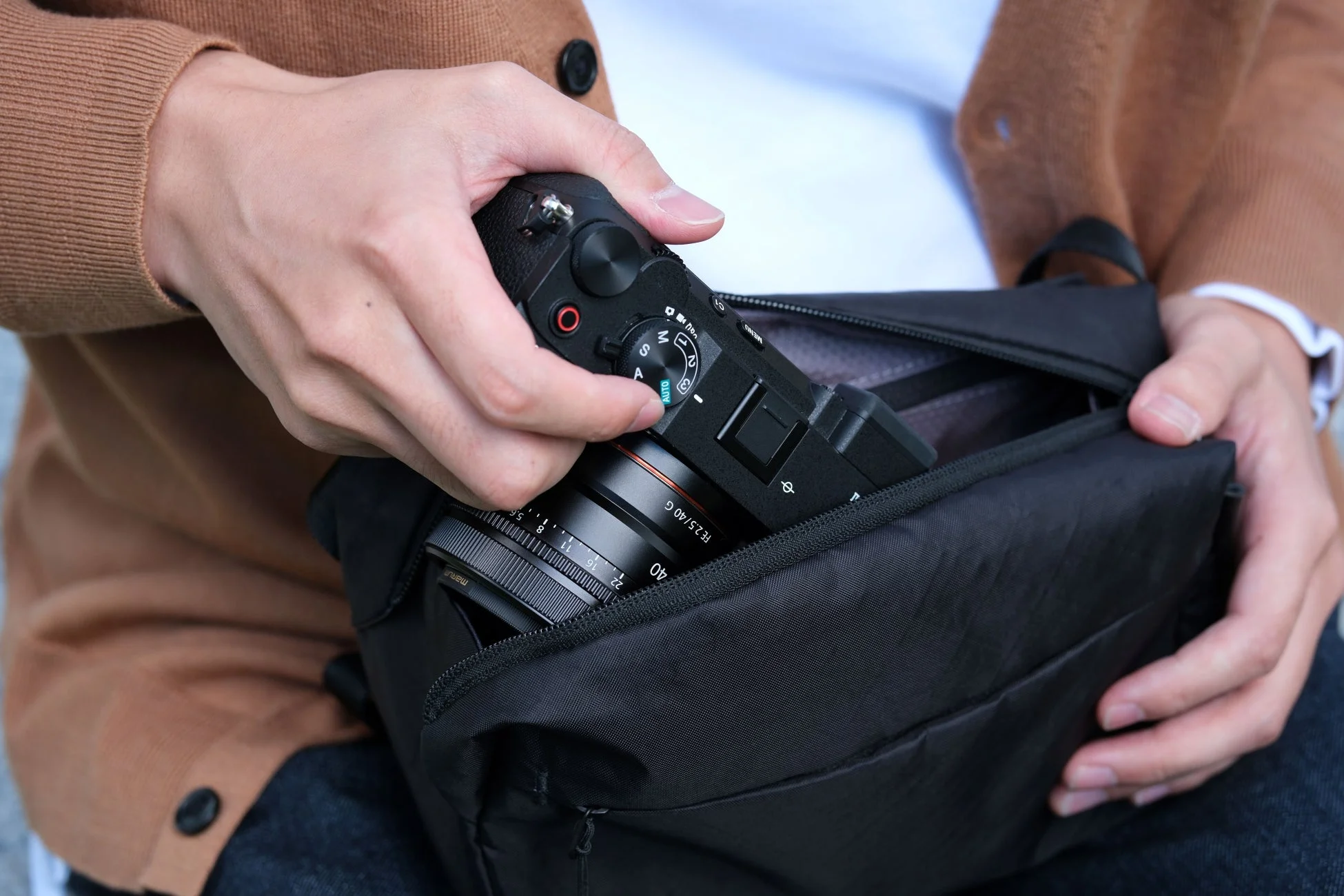 ミラーレスカメラとレンズをカメラバッグに収納する様子
