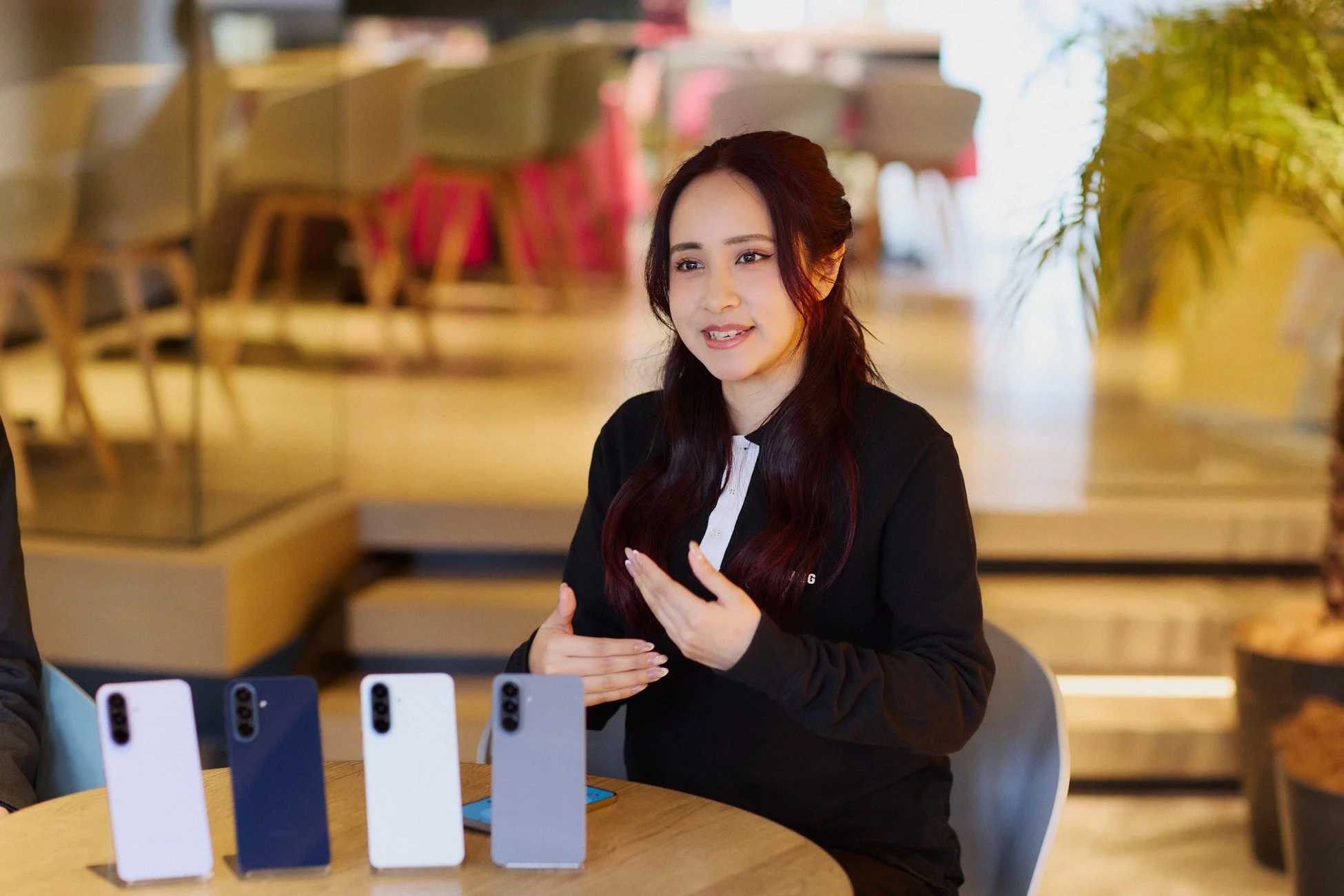 屋内会場でスマートフォン製品について説明する女性