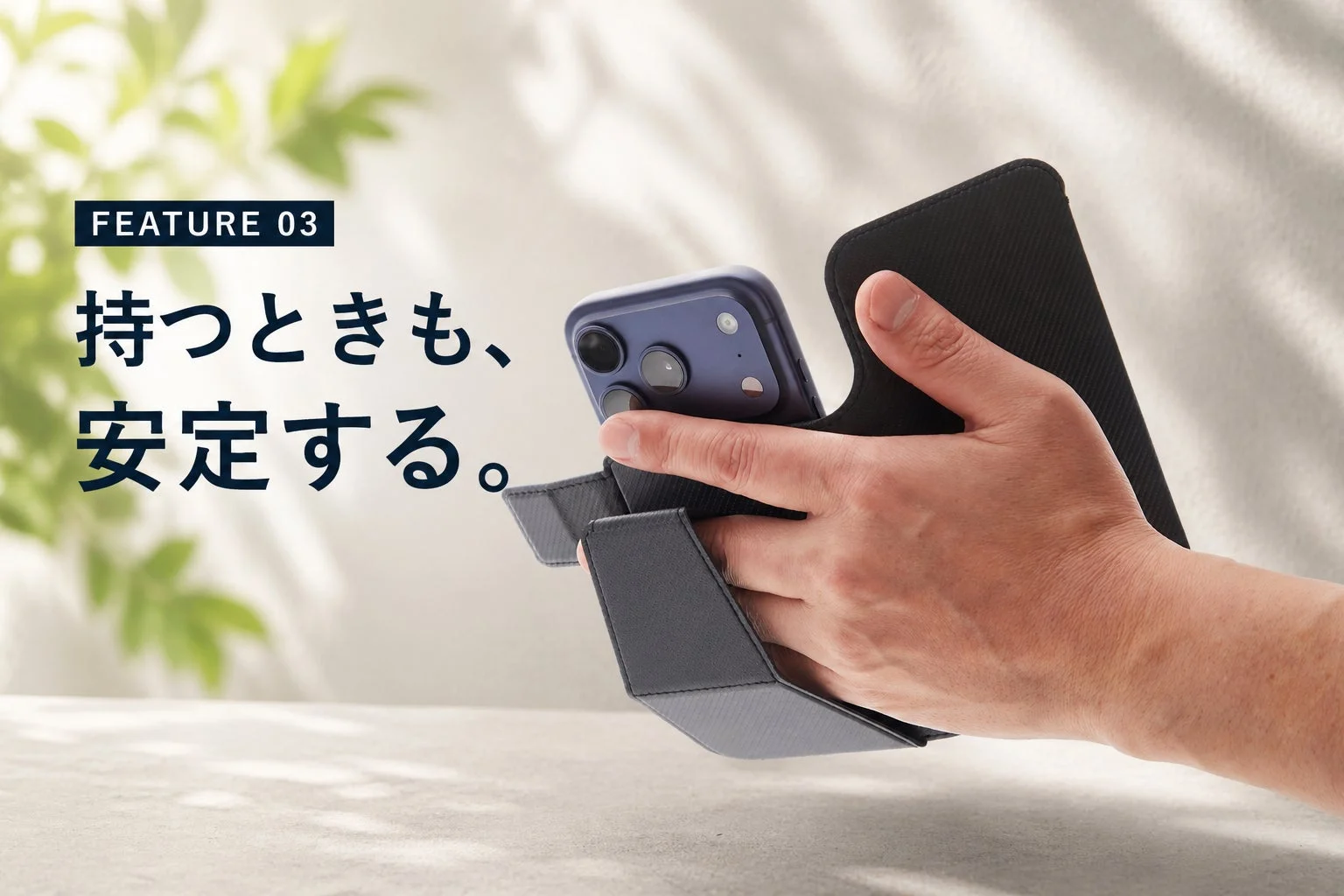 手帳型スマホケースの機能を紹介する画像です。指を差し込むことでスマートフォンを安定して持てる様子が写されており、「持つときも、安定する。」というテキストが添えられています。