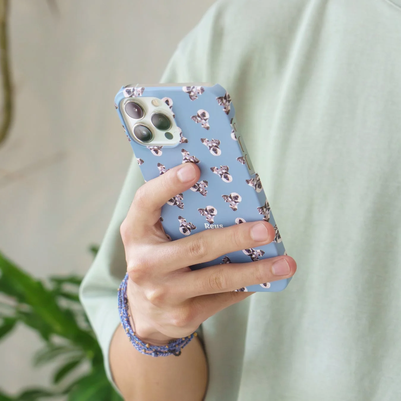 フレンチブルドッグ柄のスマホケースを装着したiPhoneを持つ手元のクローズアップ写真