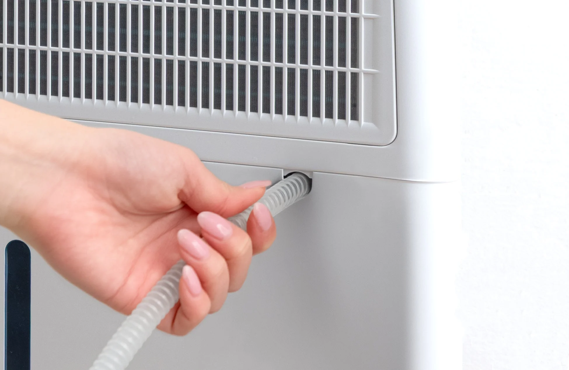 白い家電製品に排水ホースを接続する手元