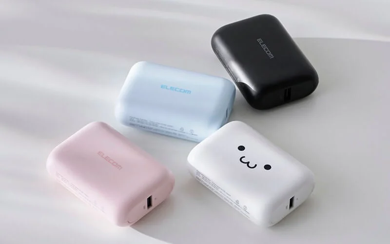 ピンク、水色、黒、そして可愛い顔の絵文字が描かれた白の4色のELECOM製モバイルバッテリーが並べられています。