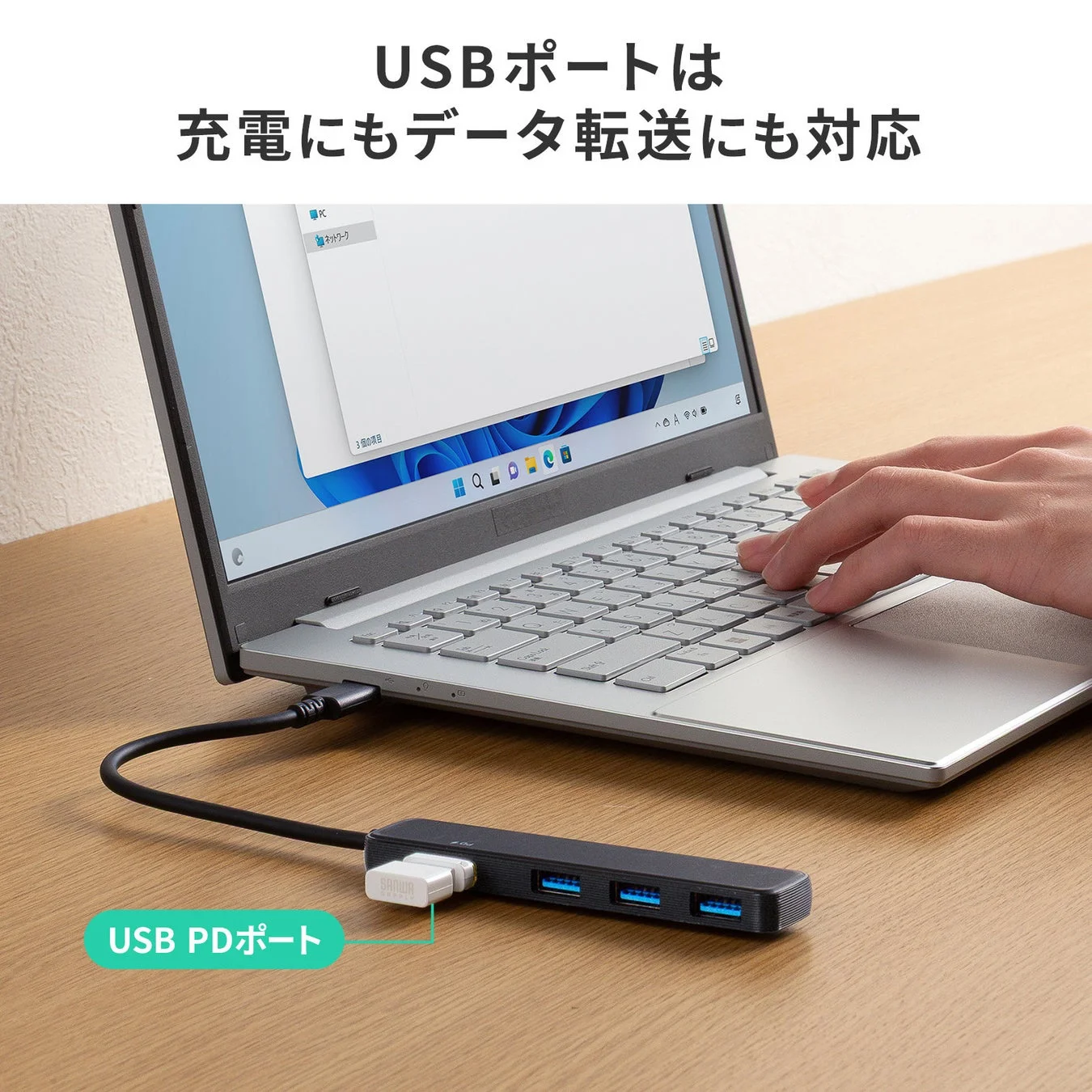 ノートパソコンにUSBハブが接続されており、USB PDポートを含む複数のポートが充電とデータ転送に対応していることを示しています。デスク上で効率的に作業する様子が伺えます。