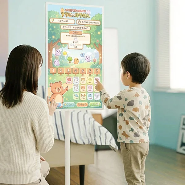 子供と大人がリビングで大型のタッチスクリーンを使って知育ゲームを楽しんでいる様子