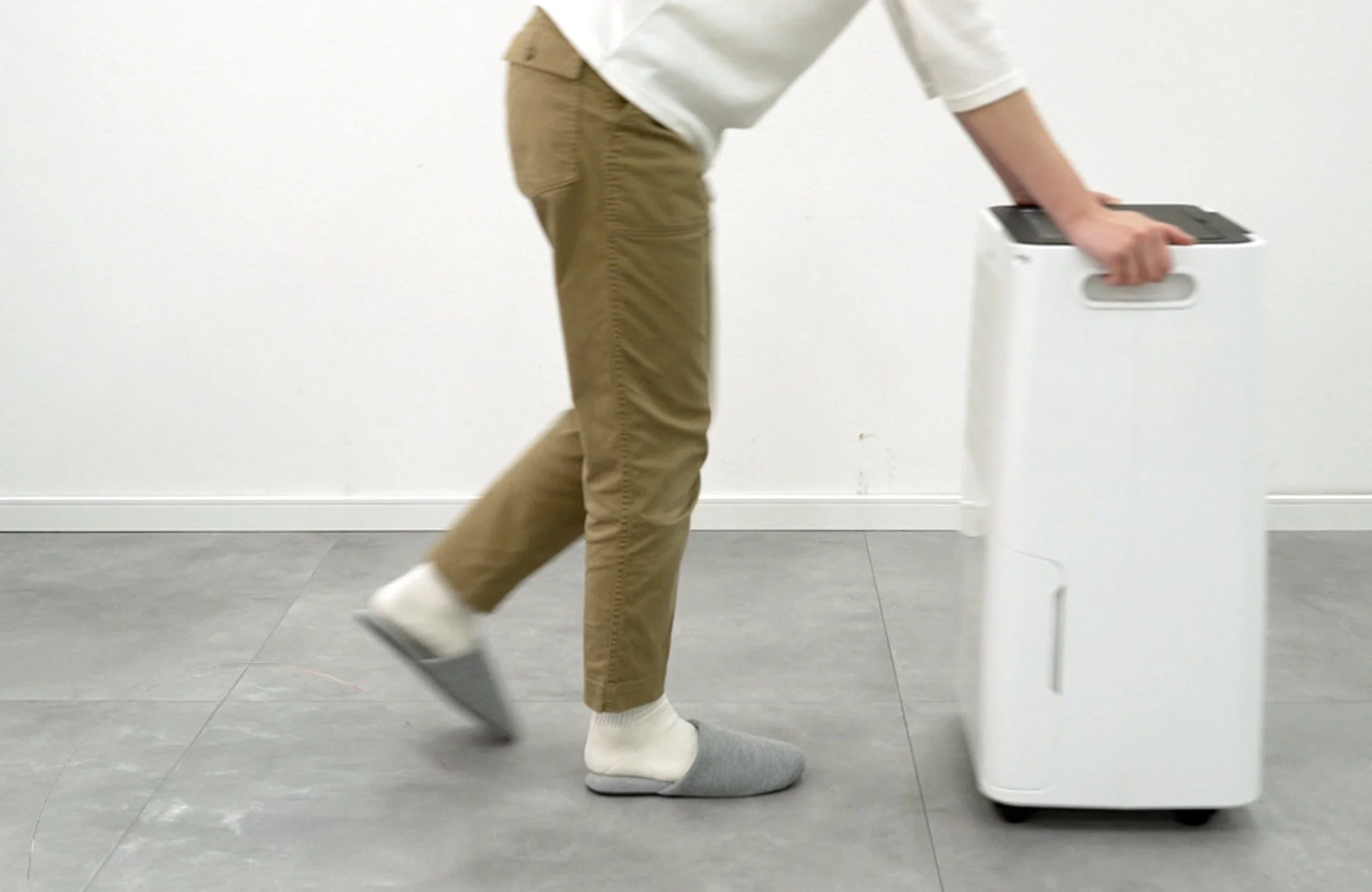 キャスター付きの白い家電製品を動かす人物