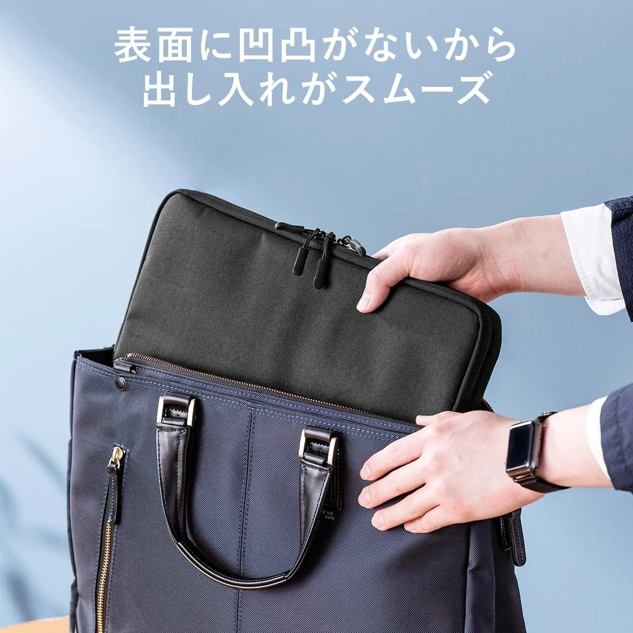 男性が紺色のビジネスバッグに黒いパソコンケースを出し入れしている様子