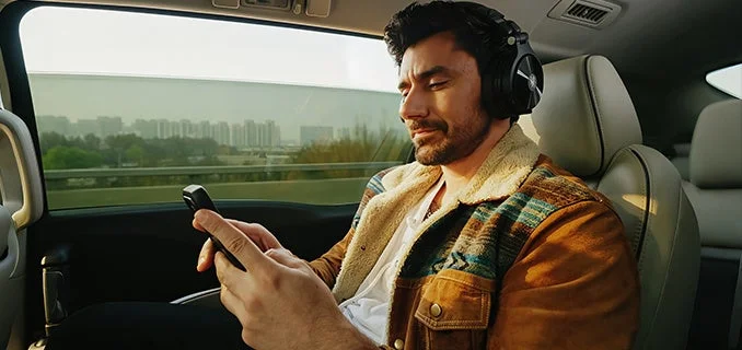 車内でヘッドホンを装着しスマートフォンを操作する男性