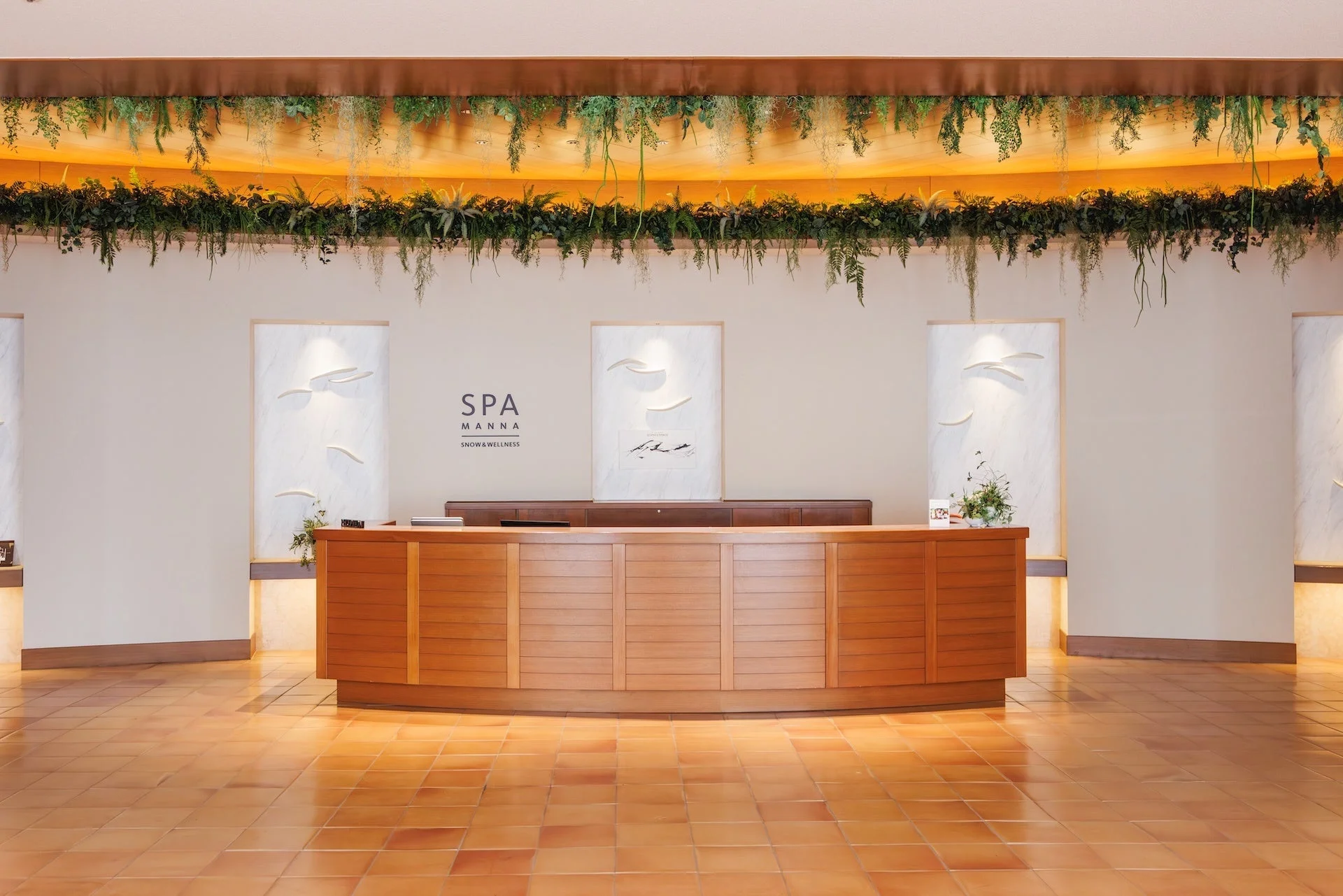 緑豊かな装飾と暖色系の照明が特徴的なスパ「SPA MANNA」の受付カウンターエリア