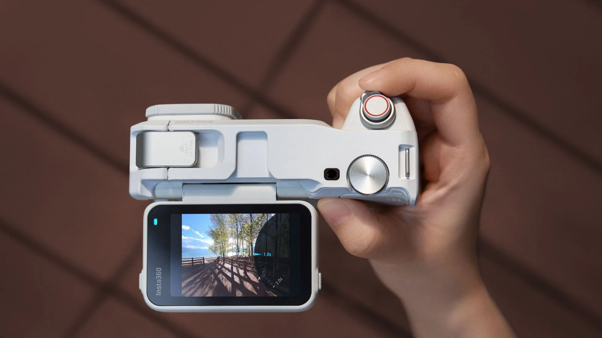 白いInsta360のモジュラーカメラを人物が手に持っているクローズアップ画像