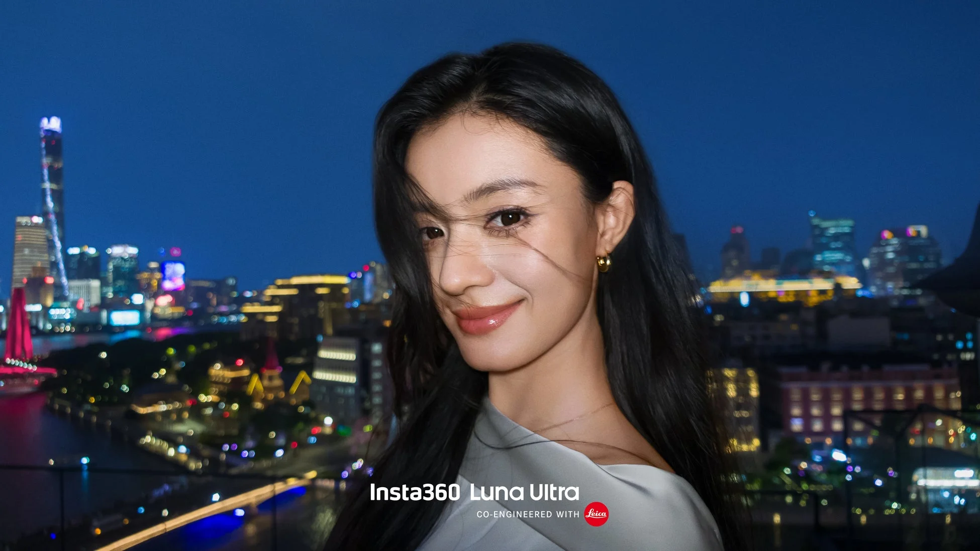 夜の美しい都市を背景に、柔らかな笑顔を見せる長い黒髪の女性のポートレートです。街の明かりが華やかに輝き、水面に反射しています。画像下部にはInsta360 Luna UltraとLeicaのロゴが見えます。
