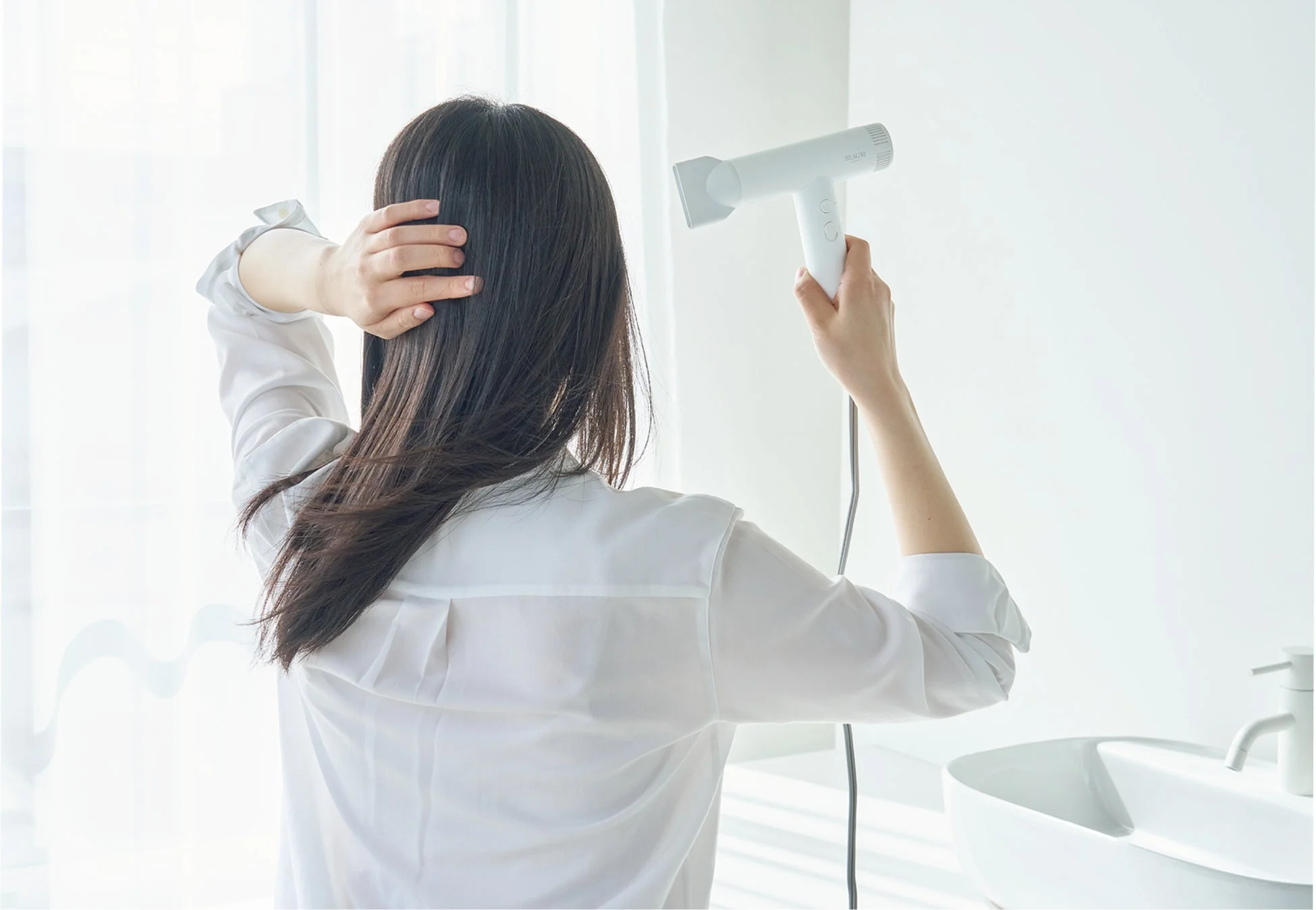 女性がヘアドライヤーを使用している様子
