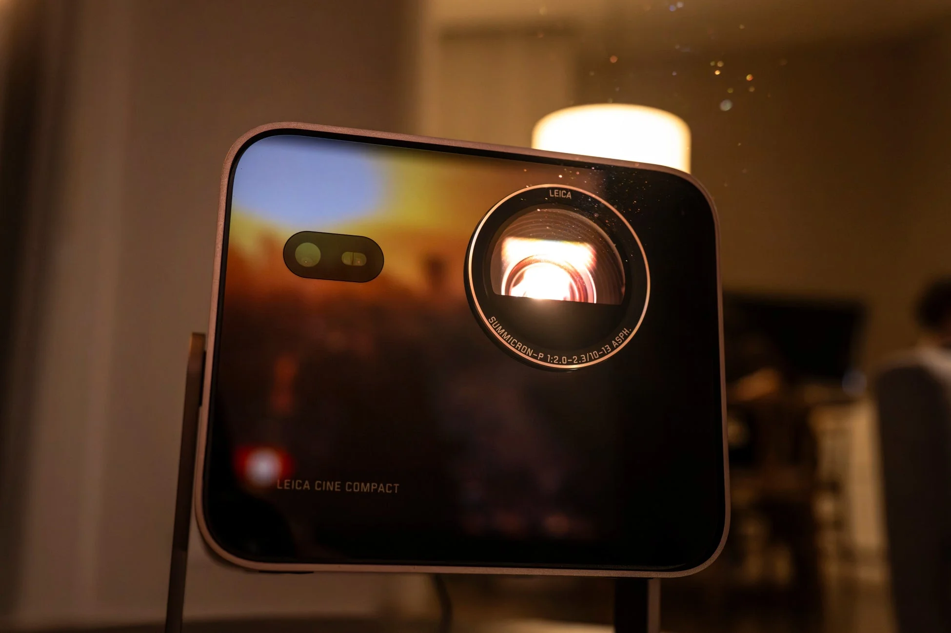 暗い室内で輝くレンズが特徴的な、Leica Cine Compactプロジェクターのクローズアップ画像