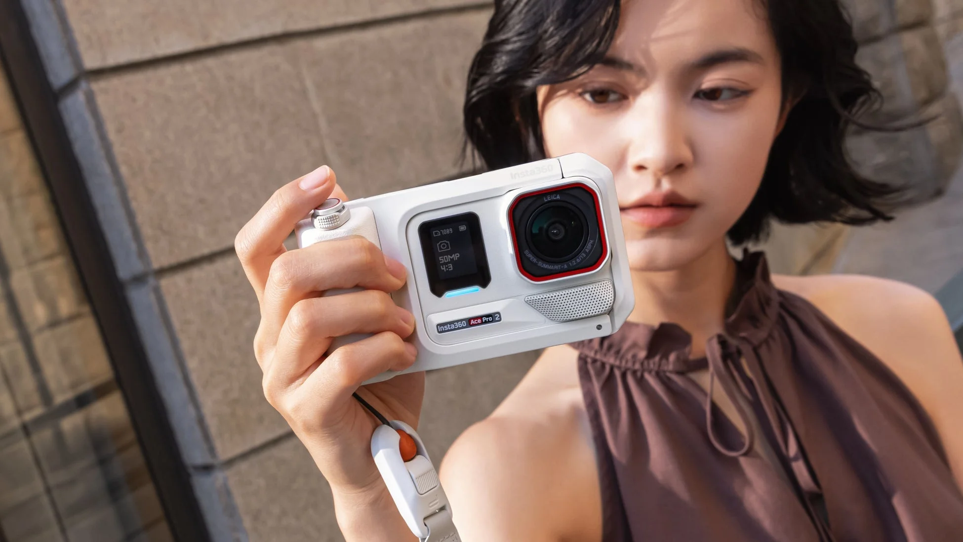 ショートヘアの若い女性が白いInsta360 Ace Pro 2アクションカメラを手にしている