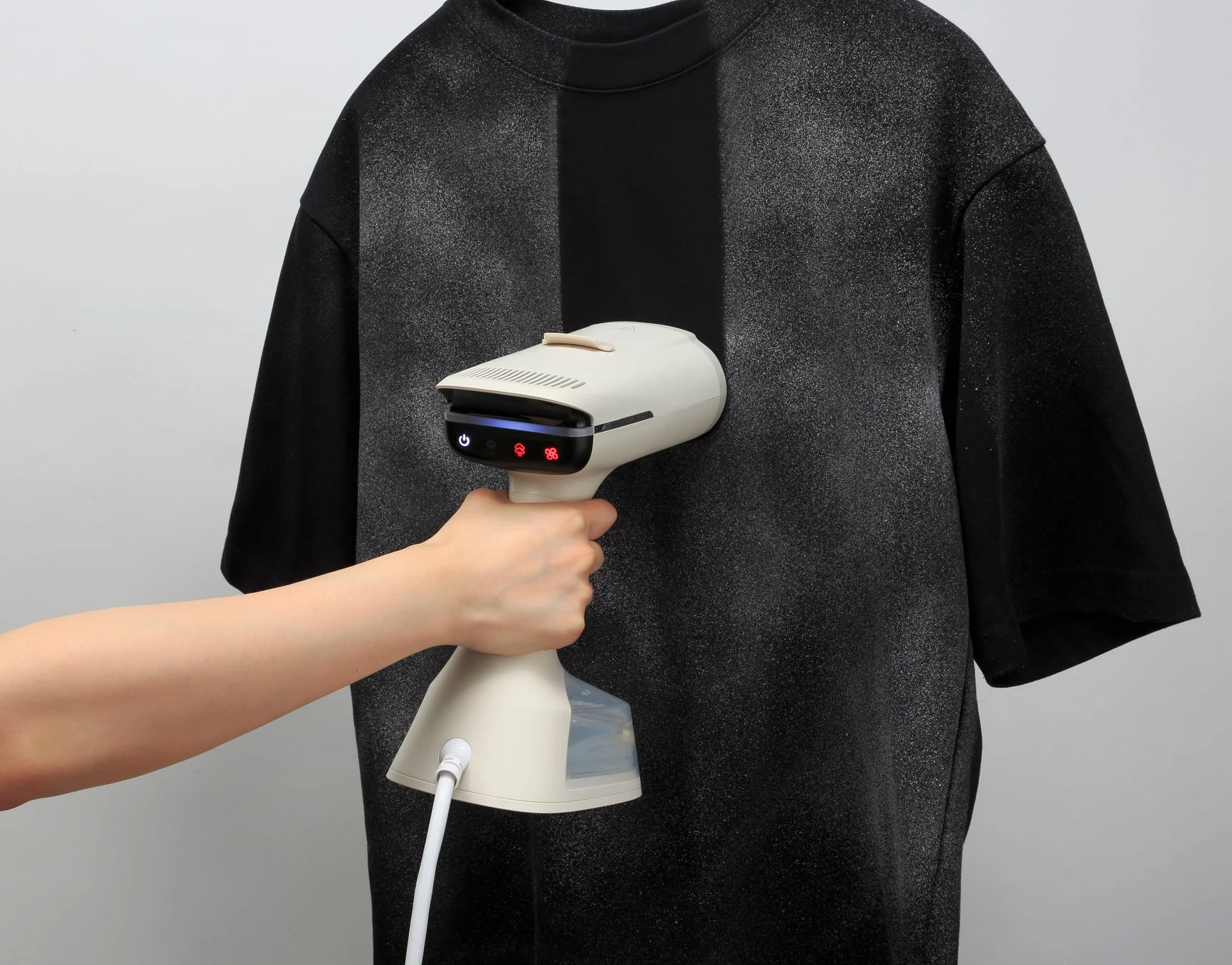 黒いTシャツにしわ伸ばしをするハンディ衣類スチーマー