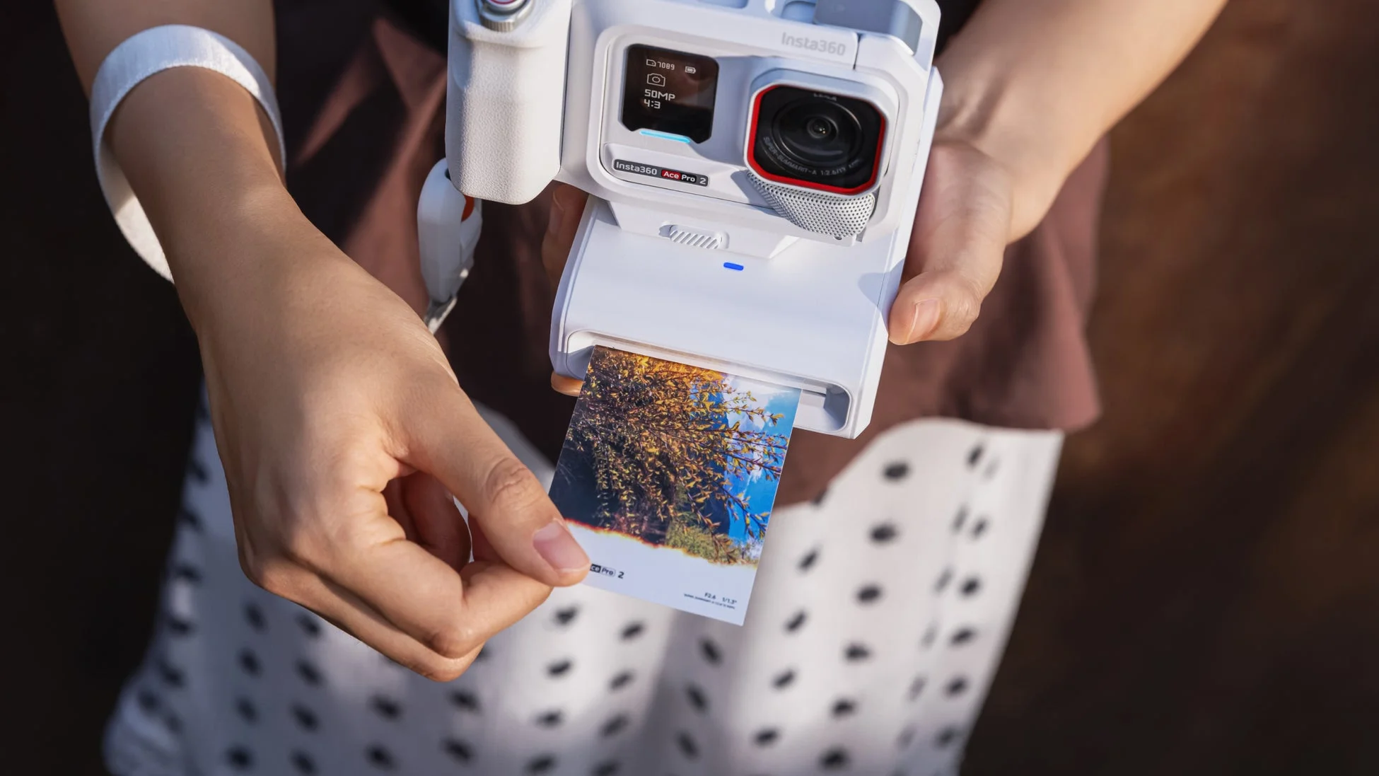 Insta360 Ace Pro 2カメラを手に持った人物がインスタントプリンターから紅葉の写真をプリントアウトしている