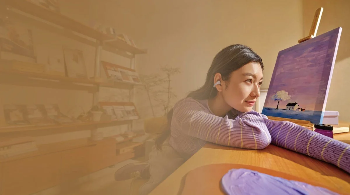 イヤホンをつけ、テーブルに腕を置いて絵画を鑑賞している女性の横顔。