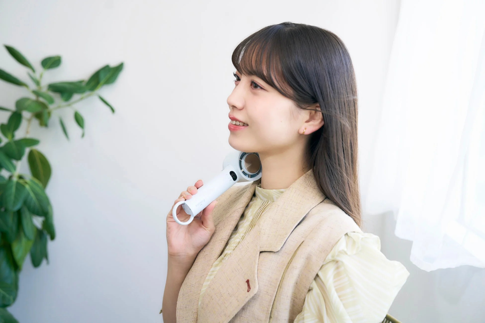 首元をハンディファンで冷やす女性