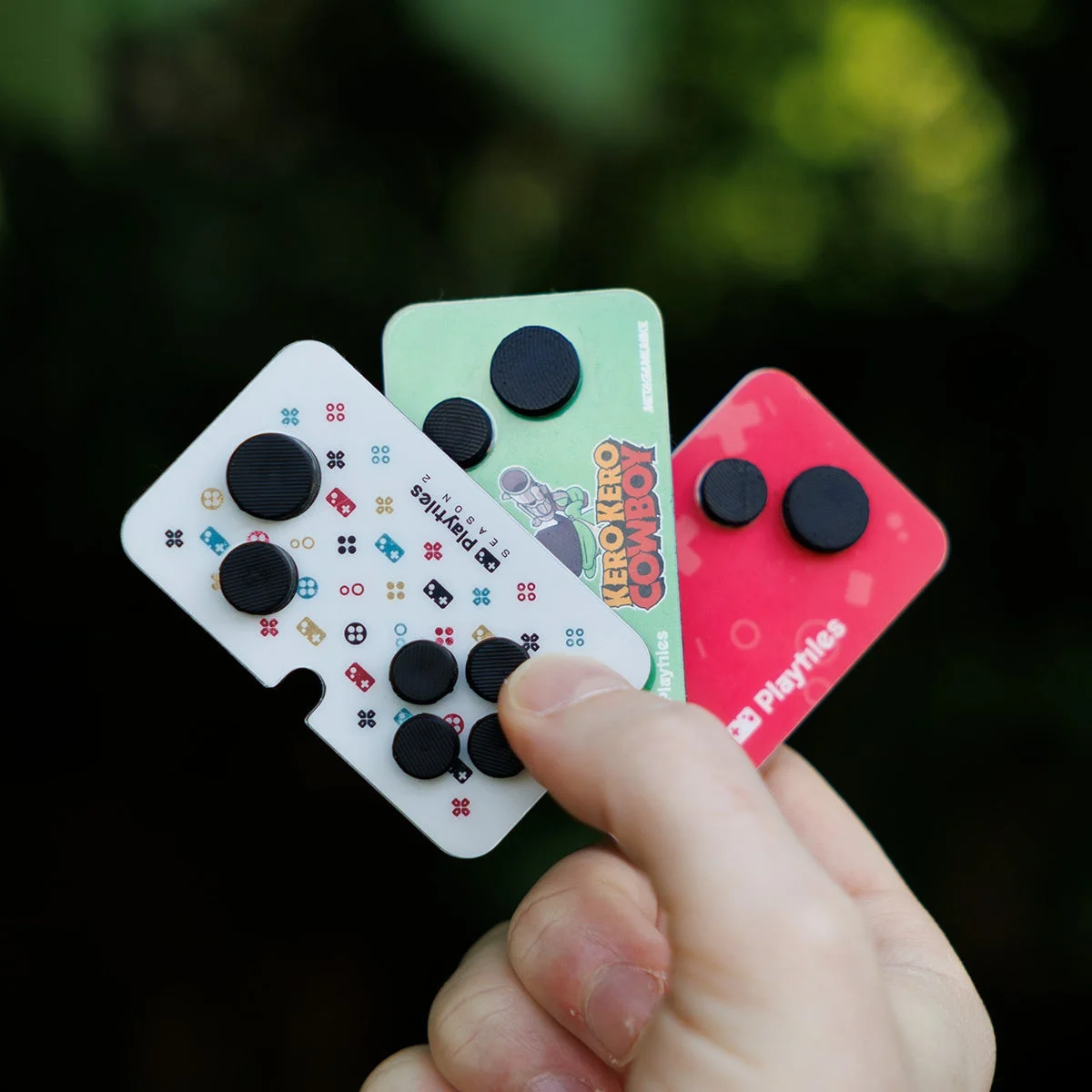 屋外で3枚のカード型ゲームアクセサリーを持っている様子
