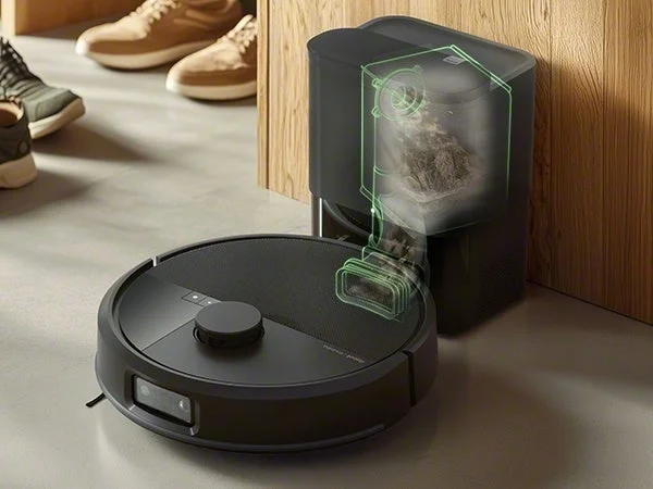 黒いロボット掃除機が自動ゴミ収集ステーションに接続されている様子。ステーションの内部には、ロボットから吸い上げられたゴミが溜まる様子が透けて見え、効率的な清掃システムを示唆しています。