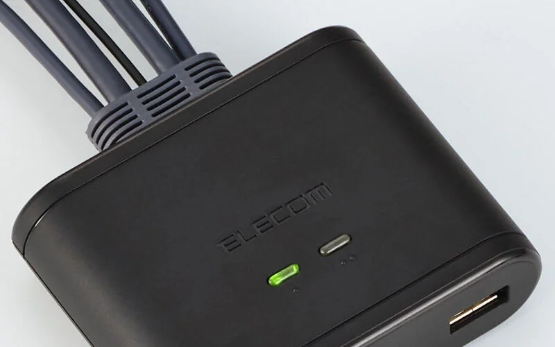 黒いELECOM製の電源タップまたはUSBハブが写っています。複数のケーブルが接続されており、前面にはUSBポートと緑色のインジケーターライトが見えます。