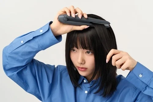 ヘアアイロンで髪をスタイリングする女性