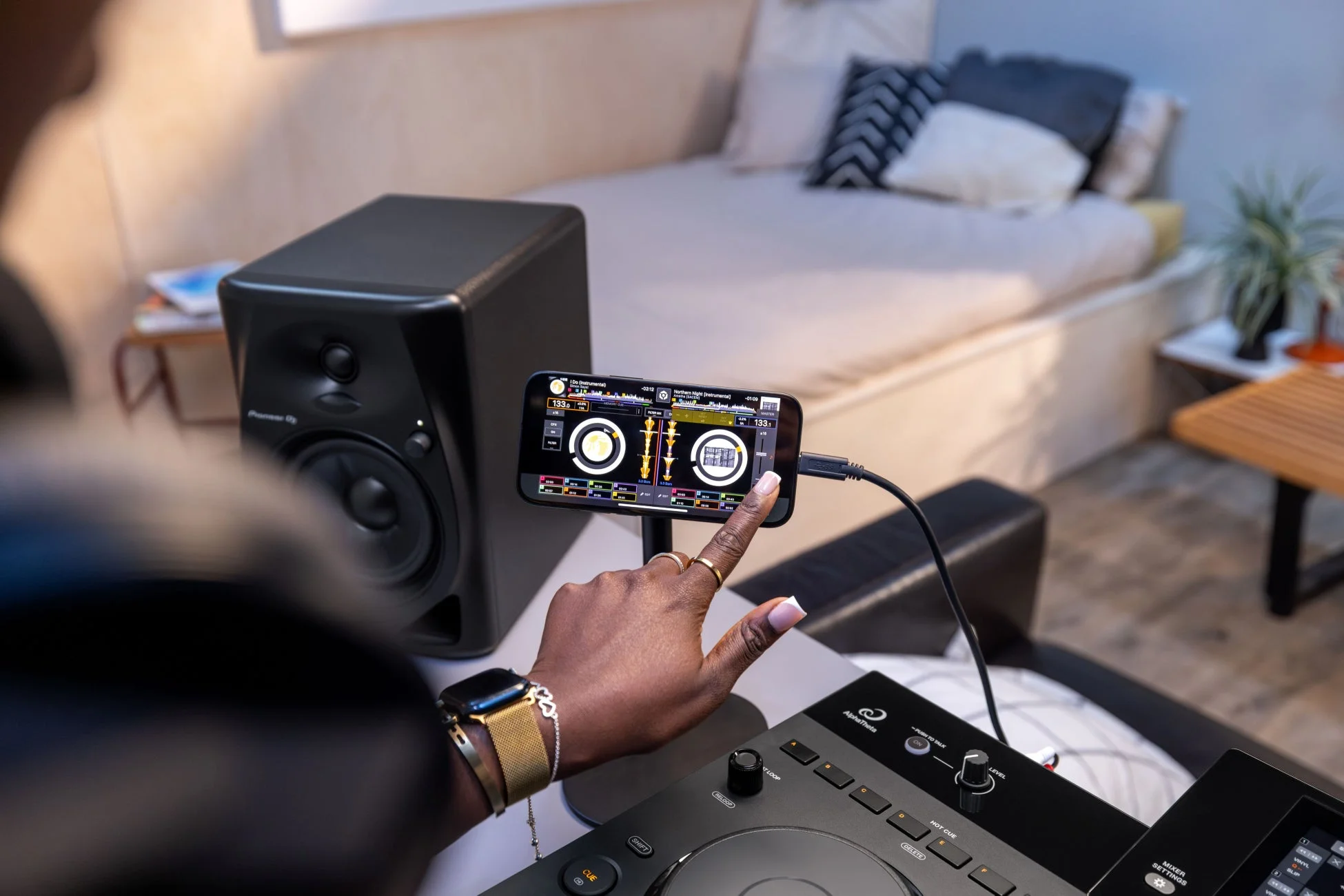 部屋でDJ機材とスマートフォンを使って音楽をミキシングしている様子
