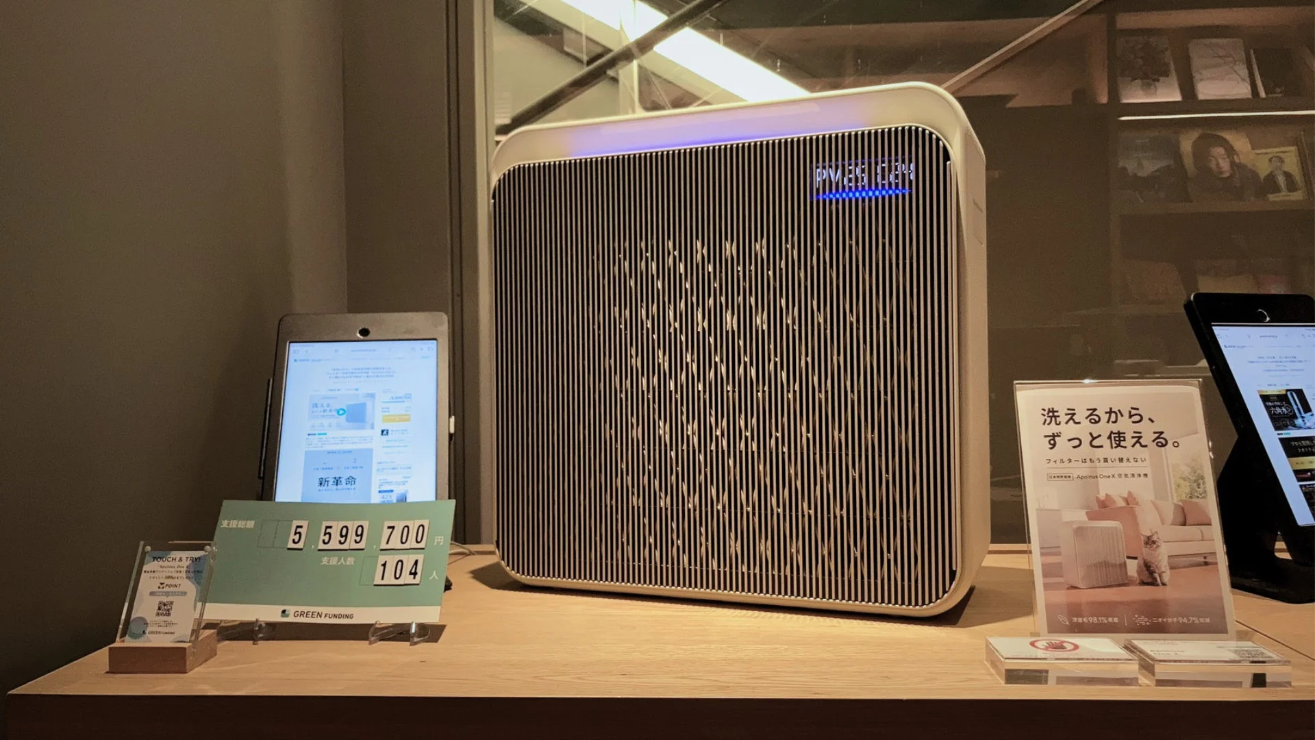 PM2.5の表示がある空気清浄機が中央に置かれ、その左右にタブレットや説明の展示物が配置されています。